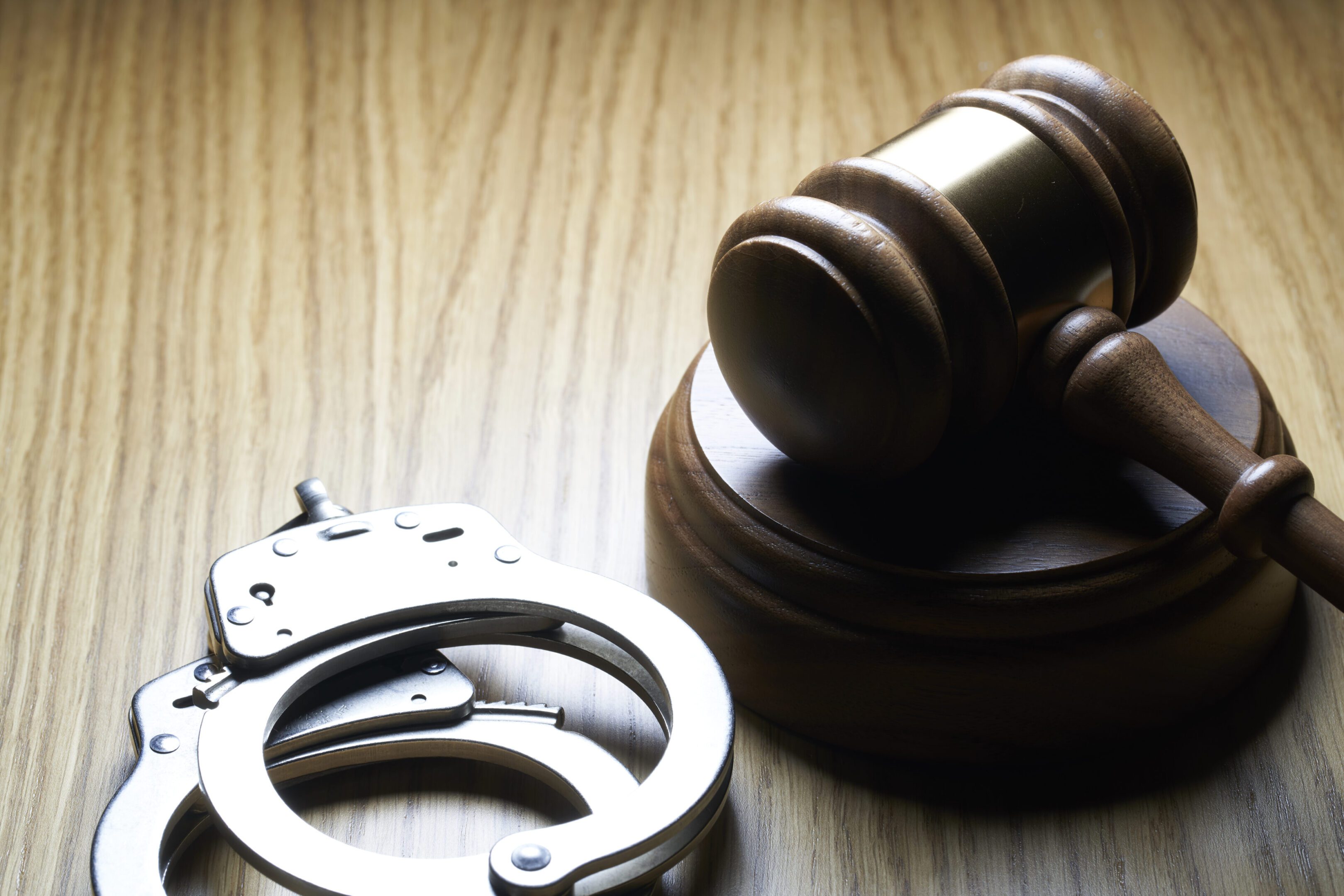 Gavel and handcuffs on wood table: